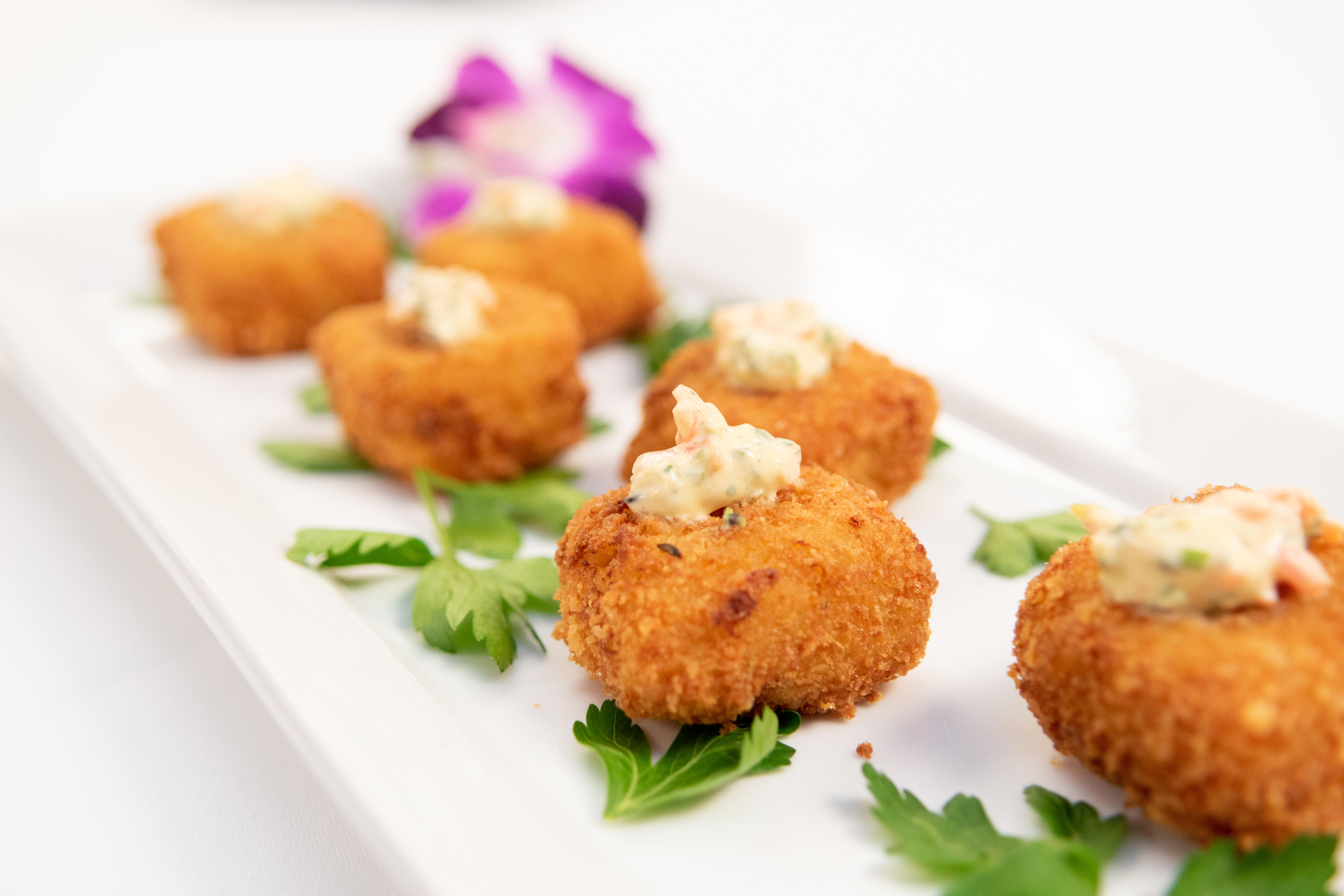 cutlet sized crispy food items served on a white tray which has cilantro for decoration